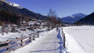 Ein spätwinterliches Alpental mit Langlaufloipe.