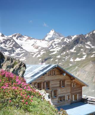 Berghütte mit schneebedeckten Gipfeln im Hintergrund