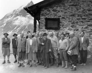Historisches Foto von Gruppe von Männern vor steinerner Berghütte