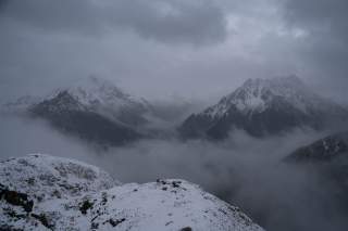 Ausblick auf die Gipfel im gegenüberliegenden Tal bei Wolken und Nebel.