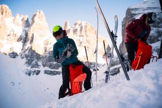 Zwei Wintersportler auf Skitour in den Alpen, die mit robusten und isolierenden Jacken von Mountain Equipment ausgestattet sind.