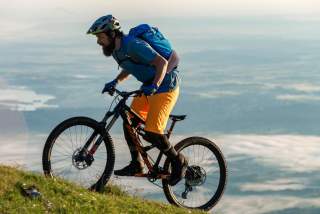 Mountainbiker fährt steile Bergwiese hoch