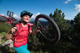 Mountainbikerin, die ihr Rad trägt