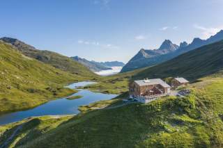 Berghütte in Almlandschaft mit kleinem See