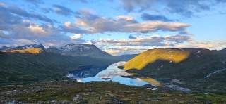 Der Abendhimmel spiegelt sich in einem stillen See in baumloser Fjelllandschaft