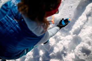 Person sucht mit LVS-Gerät im Schnee
