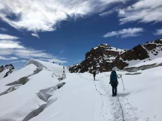 Menschen in Seilschaft laufen über Gletscher