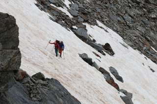 Zwei Bergsteiger queren ein steiles Schneefeld.