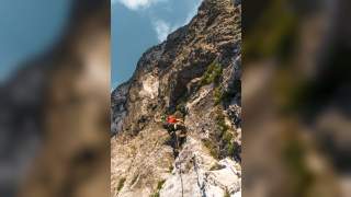 Mensch an Seil klettert in felsigem Gelände hinauf