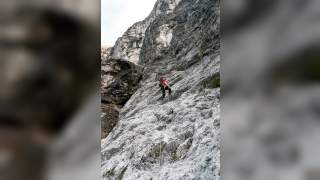 Mensch steigt an Seil steilen Fels hinauf