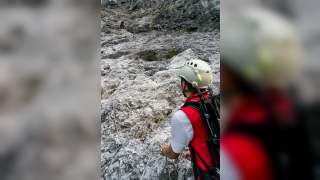 Eine Person sichert eine andere beim Aufstieg durch eine felsige Wand