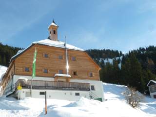 Die Bochumer Hütte, mit einem hellen Holzgiebel, in verschneiter Winterlandschaft.