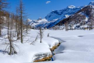 Schneebedeckte Hochebene mit Bächlein und Hütten