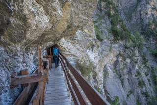 Frau wandert auf Holzbrücke unter Felswand