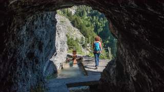Blick auf Wanderin, die aus Tunnel hinausläuft