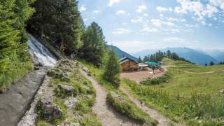 Wanderweg neben Bach führt auf kleine Almhütte zu