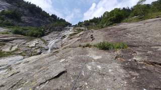 Zwei Kletternde an Wand neben Wasserfall