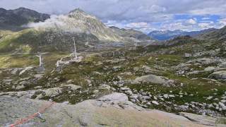 Ausblick auf Hochtal mit Gipfeln und Windrädern