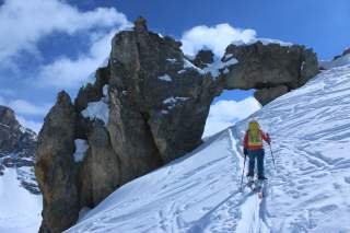 Skibergsteigerin vor einer Felsentor - einem riesigen natürlichen Durchgang im Fels.