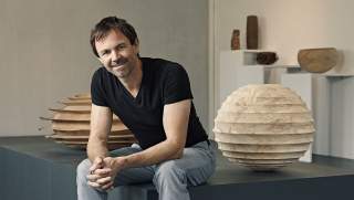 Der Holzkünstler Christoph Finkel neben einer seiner  Skulpturen