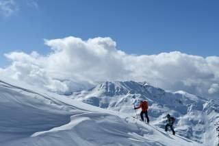 Ein Mann und eine Frau steigen auf Ski einen Berghang hinauf.