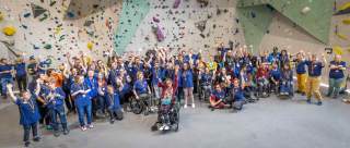 Eine Gruppe behinderter Kletternder vor einer Kletterwand in einer Kletterhalle.