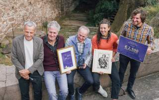 Fünf Menschen sitzen auf Mauer mit Urkunden