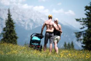 Paar steht mit Kinderwagen vor Bergkulisse