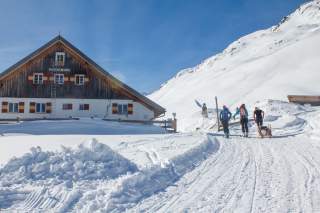 Drei Frauen gehen über einen verschneiten Weg zur Potsdamer Hütte und sind gleich dort.