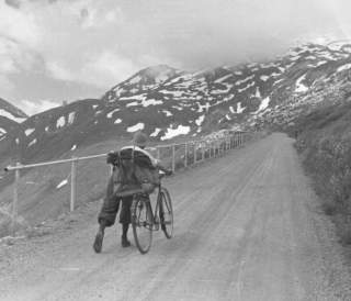 Historisches Bild von Mann der sein Rad auf Forststraße hochschiebt