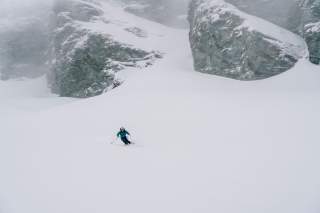 Mensch fährt in nebligen Verhältnissen durch Tiefschnee