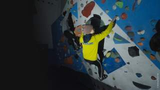 Kletterer mit gelber Jacke mit Ukraine-Schriftzug an Kletterwand