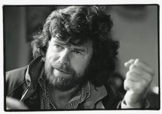 Schwarz-weiß-Porträt eines Mannes mit dichtem lockigem Haar und Vollbart, der etwas erklärt und die rechte Faust leicht vor sich hält.