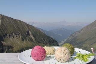 Verschiedene Knödel auf Teller, dahinter Blick ins Tal