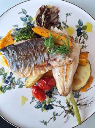 Fischgericht auf einem bunten Teller.