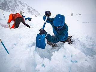 Menschen schaufeln am Berg im tiefen Schnee