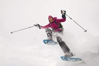 Frau mit Schneeschuhen im Schneegestöber