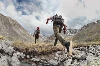 Zwei Wanderer mit einem leichten Rucksack in einem Bergtal.