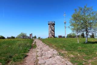 Flacher Berggipfel mit Aussichtsturm und Handymast.