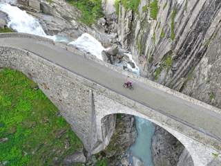 Drohnenaufnahme von Radfahrer der über Brücke über tiefe Schlucht fährt