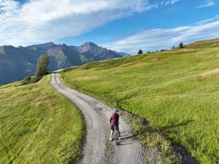 Gravelbiker auf breitem Schotterweg in den Almkulisse