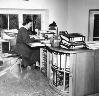 Historisches Schwarz-Weiß-Foto von Frau an Schreibtisch