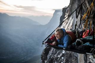 Mann liegt auf Portaledge in Felswand