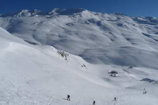 Tief eingeschneite Bergwelt mit Menschen, die Skitouren gehen
