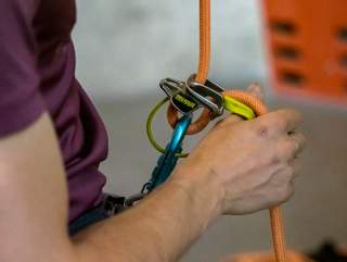 Nahaufnahme einer Person beim Sichern in der Kletterhalle