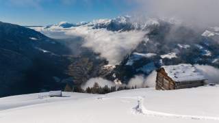 Aufstieg zwischen zwei Hütten mit Blick ins Tal