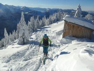 Person auf Skitour in verschneiten Bergen bei Sonnenschein