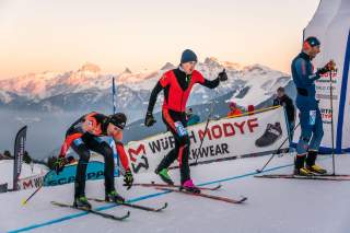 Drei Männer laufen auf Ski in Ziel ein