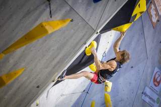 Mann klettert an Kletterwand