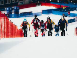 Zwei Skibergsteigerinnen, Helena Euringer links und Tatjana Paller mittig rechts, steigen mit Skiern und Wettkampfausrüstung einen steilen Hang beim Sprint-Rennen in Bormio hinau